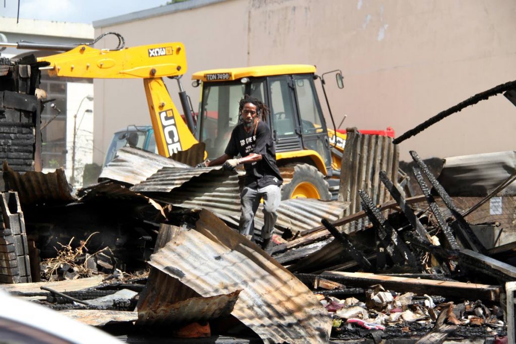 CLEAN UP: A backhoe belonging to the PoS City Corporation clears away rubble yesterday at the Drag Mall in Port of Spain a week after fire destroyed four booths. PHOTO BY SUREASH CHOLAI
