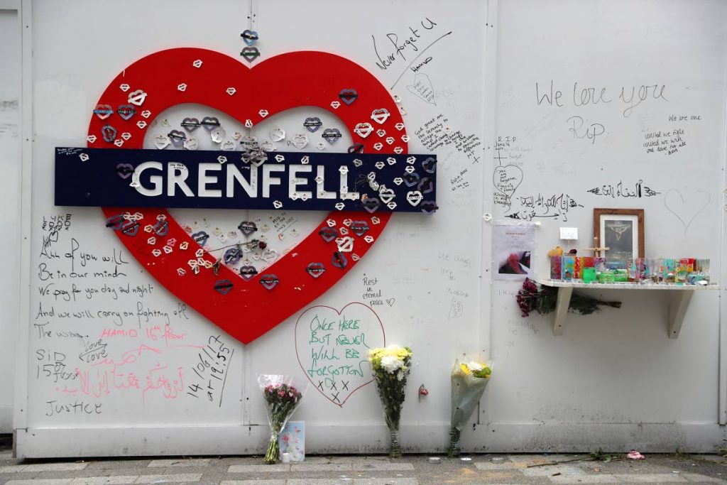 Messages of condolence for the 71 victims of the Grenfell Tower fire on a fence near to the burned-out shell of the tower block in west London last Wednesday. AFP PHOTO