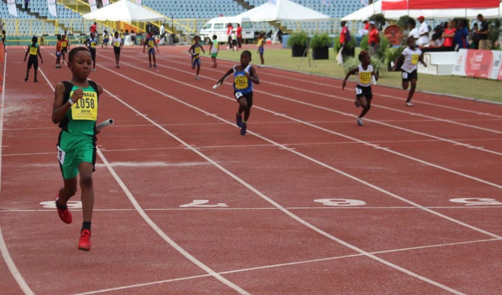 A Cougars athlete, left, sprints to gold in the Under-11 4x100m mixed relay event at the NGC NAAA National Juvenile Championships at the Hasely Crawford Stadium, Mucurapo, Saturday.