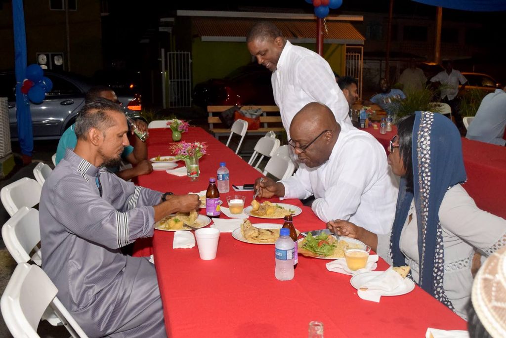 Finance Secretary Joel Jack, standing, joins Chief Secretary, Kelvin Charles, centre right,  and his wife Catherine Anthony-Charles as share an Eid-ul-Fitr celebratory meal with  Kameal Ali, coordinator and administrator for Majid al Tabwah in Lowlands on Thursday night.
