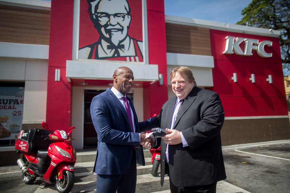 Darryl White (left), Managing Director, RBC Royal Bank Trinidad and Tobago (left), seals the partnership deal with Charles Pashley, CEO, Prestige Holdings, for the use of RBC point-of-sale devices by KFC delivery drivers.