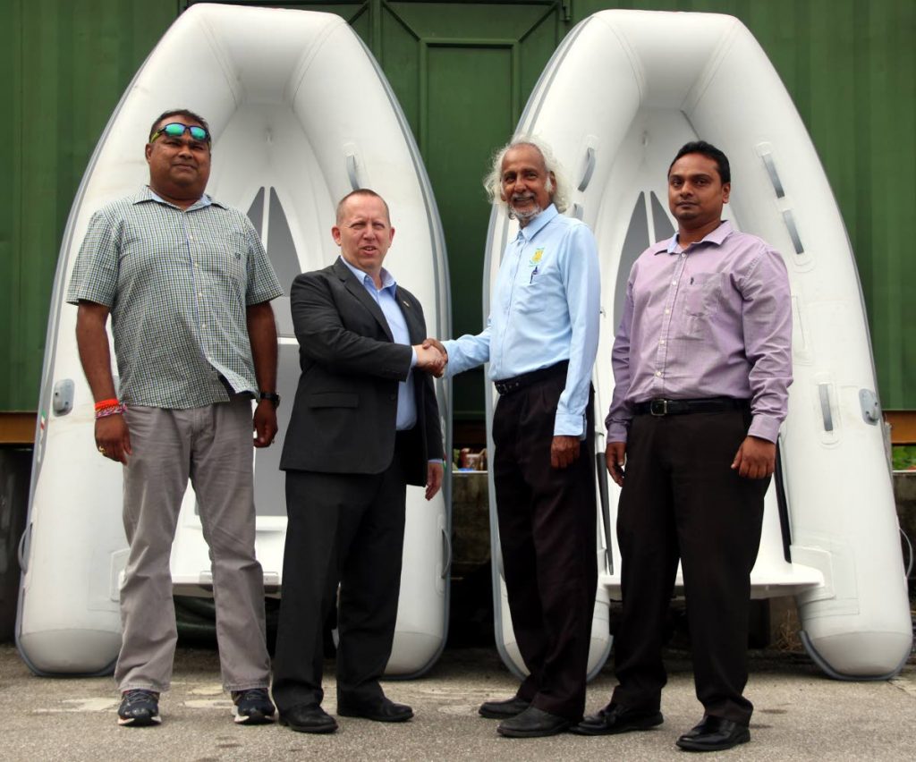 John Mclntyre Deputy Chief of Mission of the US Embassy (second from left) presents Dr Allan Sammy Chairman of the Penal Debe regional Corporation with two small boats.