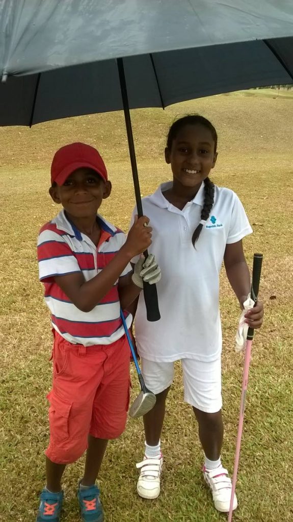 A supporter shelters Faatimah Emamalie in the Republic Bank 2015 Junior Golf Tournament at St Andrews Golf Club, Moka, Maraval. PHOTO COURTESY ALICIA EMAMALIE 
