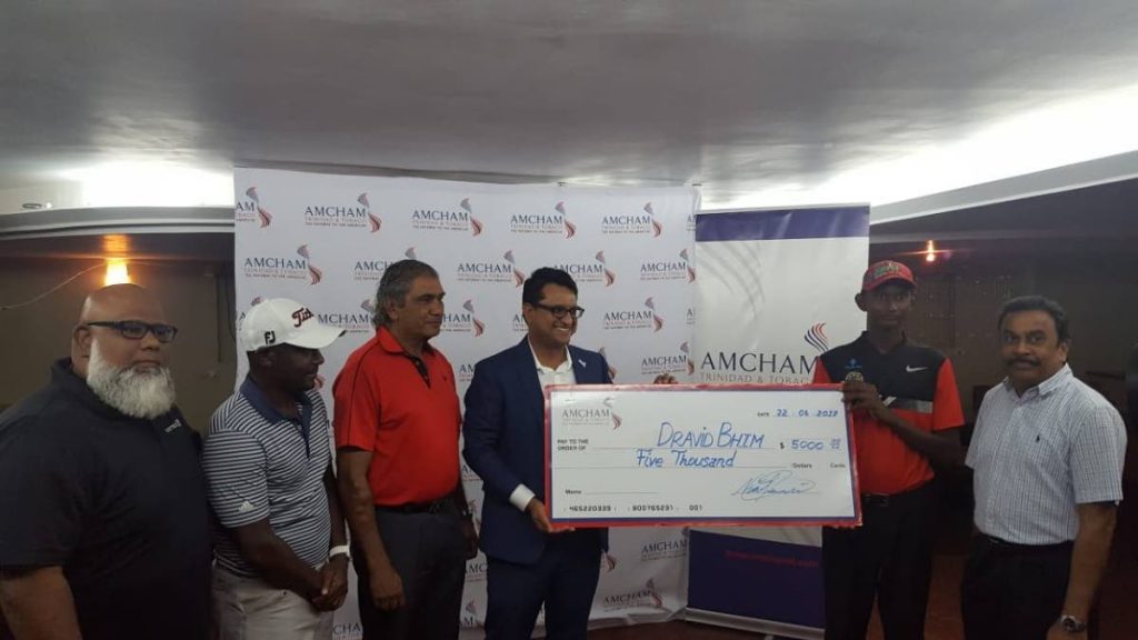 TT junior golfer Dravid Bhim, 2nd right, receives a cheque from Nirad Tewarie. From left, United Airlines representative Jason George, Russell Latapy and Clyde Abder look on during the handover. At right, is AMCHAM Committee chairman Vishnu Balroop.