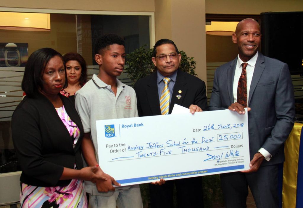 HELPING HAND: Principal of the Audrey Jeffers School for the Deaf Veronica Johnm, left, and student Terique Rougier receive a cheque from RBC Marabella branch manager Shameen Mohammed, 2nd from right, and RBC Managing Director Darryl White, right, on Tuesday at the reopening of the bank’s Marabella branch.