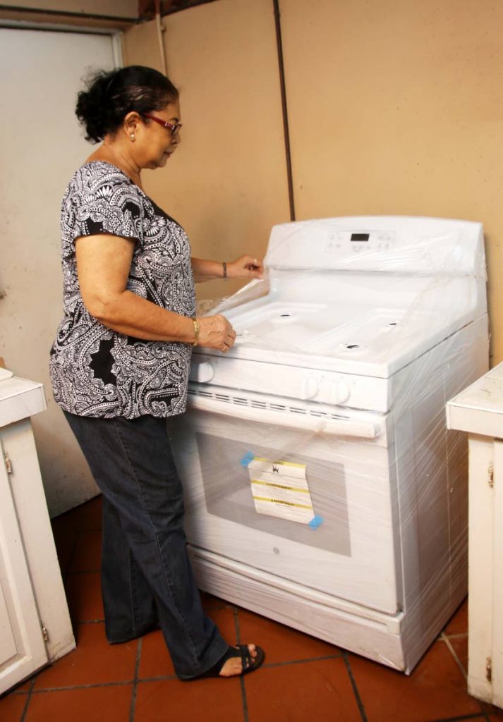 FIRE UP: Joan Lee Chong removes the plastic from a new stove which was donated to the Holy Cross RC Church, Princes Town soup kitchen by Price Club, Chaguanas.   PHOTO BY VASHTI SINGH