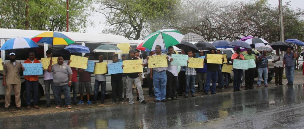 PROTEST: Despite heavy rainfall drivers of the Maxi Taxi  Concessionaires Association yesterday protested  with placards, oposite PTSC on Lady Hailes Avenue , San Fernando. PHOTO BY VASHTI SINGH