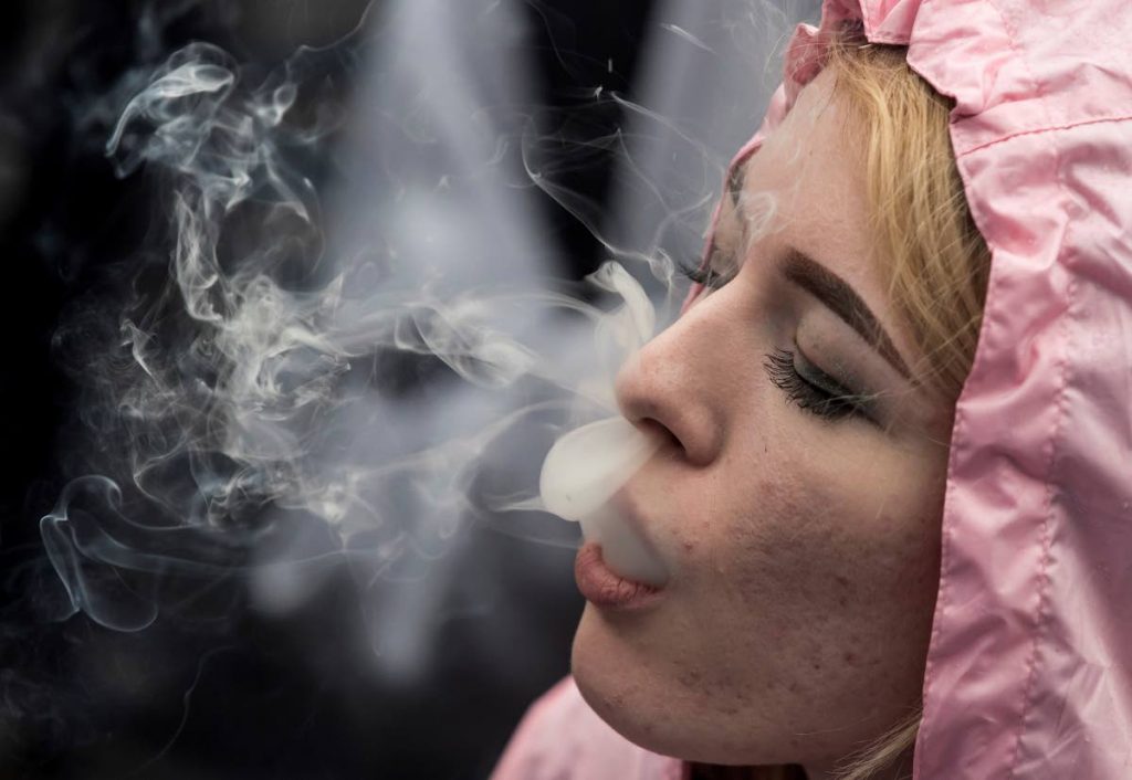 In this April 20, 2018 file photo, a woman exhales while smoking a joint during the 4-20 annual marijuana celebration, in Vancouver, British Columbia.