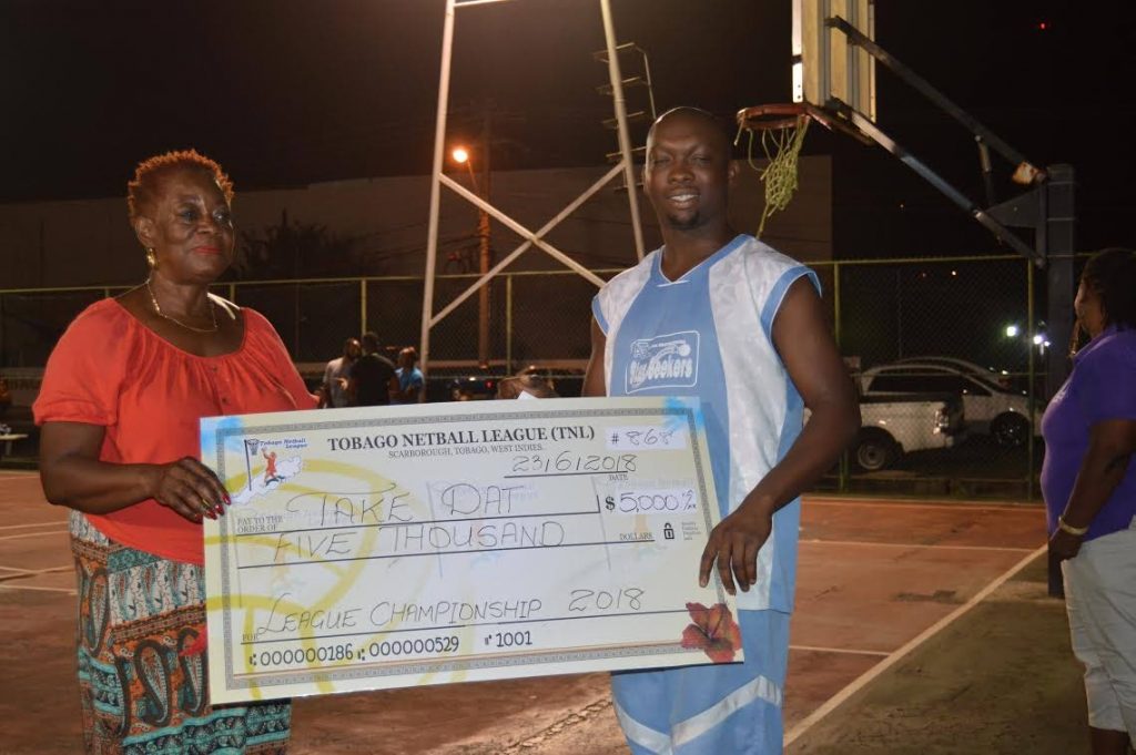 Former Tobago Netball League president Martha Archer presents Valdez Perez of Take Dat with a cheque for $3,000 after the team captured the Men’s Big Four Competition, at Shaw Park, last weekend.