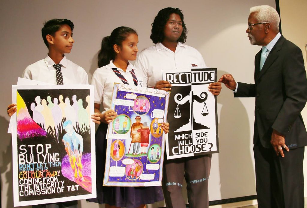 The Integrity Commission of TT Secondary Schools Poster Design Project -2018 Awards Ceremony.
At right Justice  Melville Baird ( Chairman) congratulates from 2nd right 1st place winner David Ramlakhan,of  San Fernando East Secondary School, 3rd place Rebekah Beepat of Debe Secondary and 2nd place Dylan Samaroo of Naparima Boys Secondary holding their pieces at NALIS, Port of Spain.
PHOTO BY AZLAN MOHAMMED