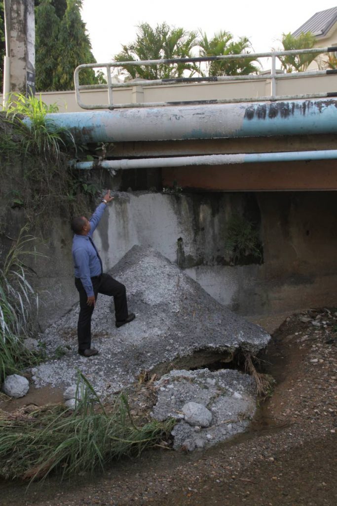 CEMENT SHAME: Newsday reporter Julien Neaves stands on a hardened mound of cement  dumped into the Maraval River at the bottom of Saddle Hill, Saddle Road over the weekend.