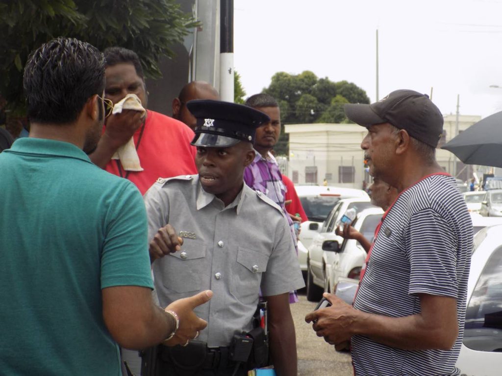 Members of the Aranguez Taxi Drivers' Association and an officer of the Traffic Branch engage in a brief exchange along the Aranguez Taxi Stand where drivers staged a protest. Photo: Shane Superville