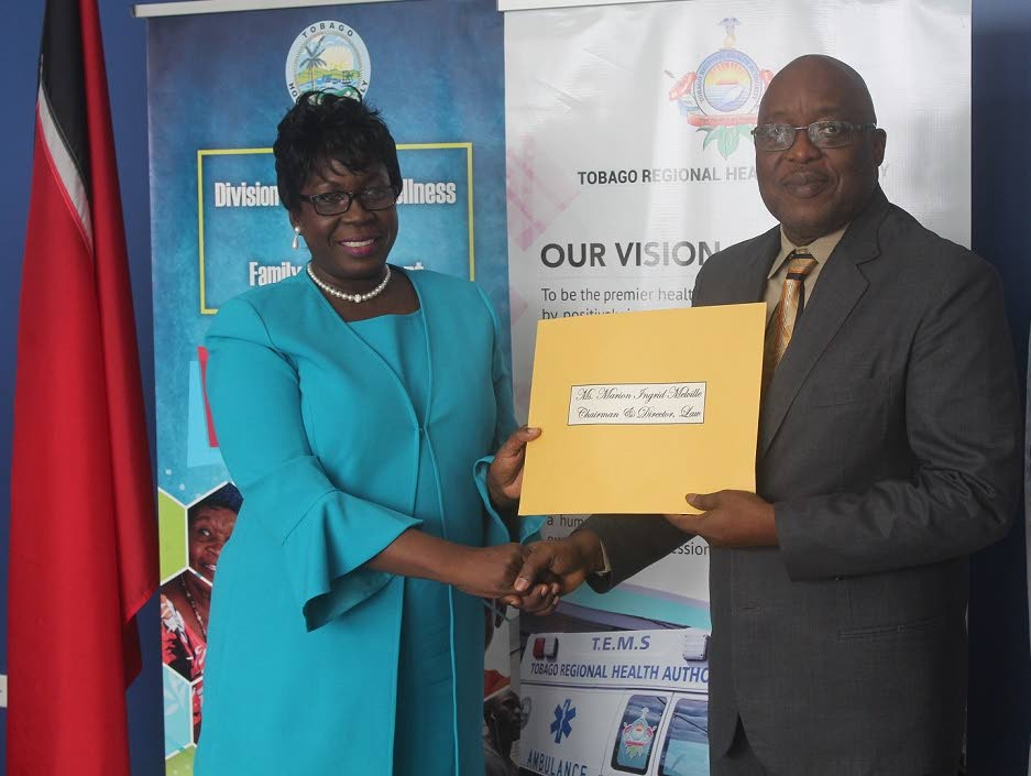 Chief Secretary Kelvin Charles presents Ingrid Melville with her instrument of appointment as Chairman and Director - Law of the Board of the Tobago Regional Health Authority (TRHA).