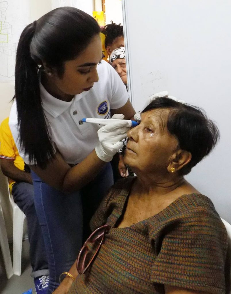 In this file photo lab technician Narissa Katwaroo examines the eye of pensioner Rosie Toolaram during a free health clinic. PHOTO BY SHANE SUPERVILLE