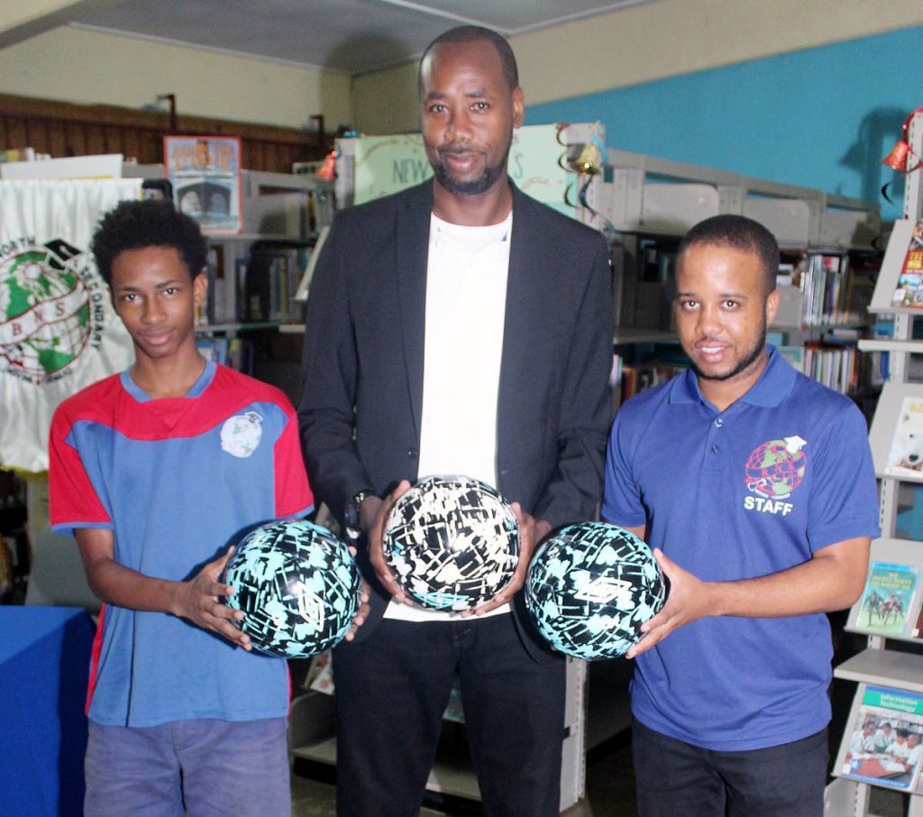 Dennis Lawrence, TT’s senior men’s football coach (C), Dimitri Gidaree (L), captain of Barataria North Secondary football team and Johan Redhead, the school’s coach, pose with footballs donated to the school by Lawrence at the school compound in Barataria yesterday.
