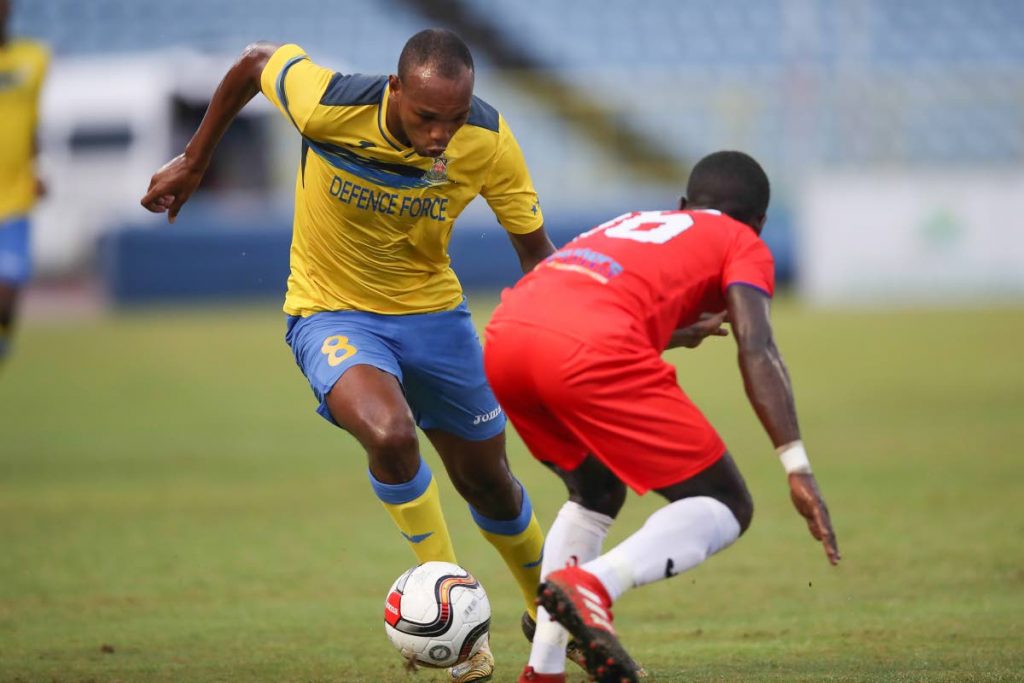 Defence Force Brent Sam attempts to dribble past Morvant Caledonia Travell Edwards in a First Citizens Cup semifinal at the Hasely Crawford Stadium, Mucurapo, Friday.