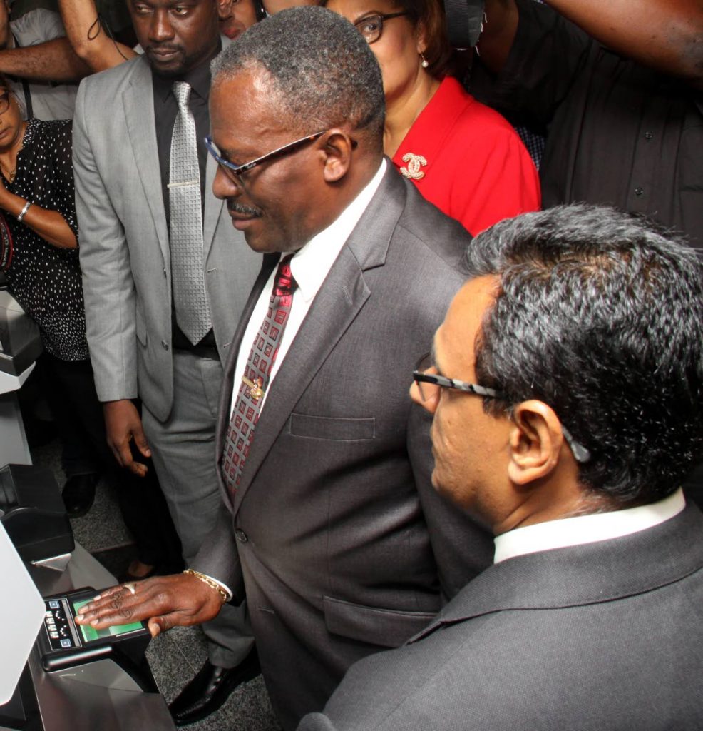 Minister of National Security Edmund Dillon tests the newly launched Automated Boreder Control System at the Piarco International Airport. Minister of Works & Transport Rohan Sinanan, right, looks on. PHOTO: ANGELO M. MARCELLE