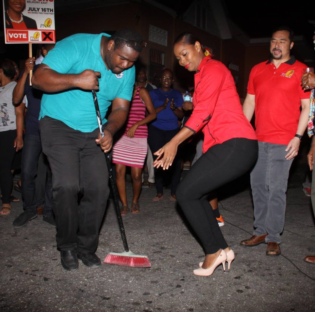 SWEEP THEM: PNM councillor-elect Nicole Young dances while PoS Deputy Hillan Morean sweeps the ground to signify the party’s dominance in the Belmont East by elections.