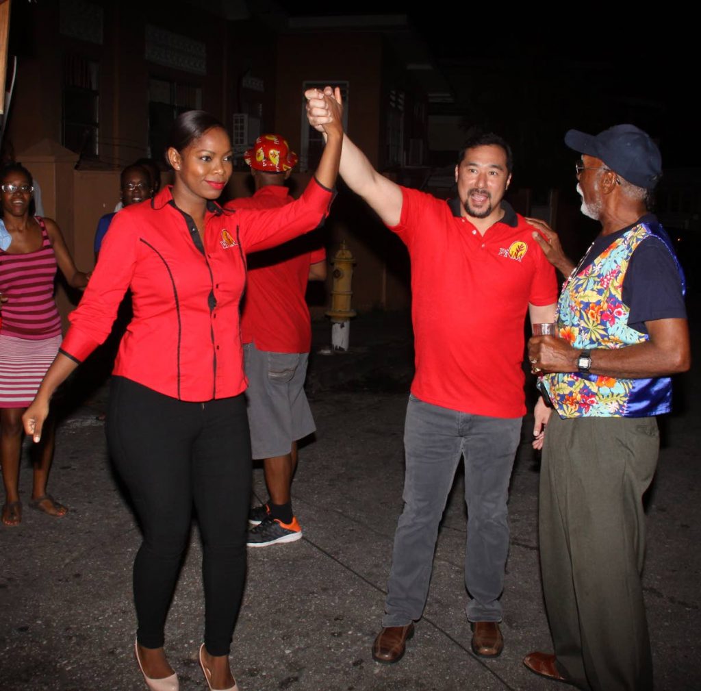 PNM’s Belmont East candidate, Nicole Young, has her hand lifted in victory by Stuart Young at the PNM’s office, Pelham Street, Belmont on Monday night.