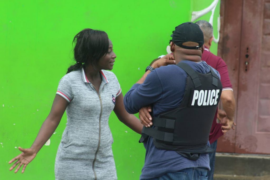 TENSION: A woman speaks with police officers in the Beetham yesterday morning, hours after fellow resident Akile “Alkaline” Thomas, 20, was shot dead by police. PHOTO BY ENRIQUE ASSOON
