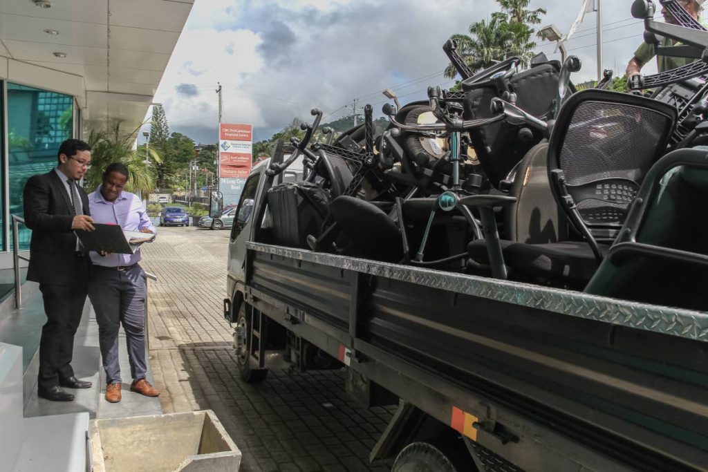 OFF IT GOES: Attorneys Joel Rooper (right) and Justin Leung go through a list of items as the are loaded onto a truck, as a result of a court judgement between Prudecon Limited and EFCL, at  Long Circular Road, Maraval, on Wednesday. PHOTO BT JEFF K MAYERS