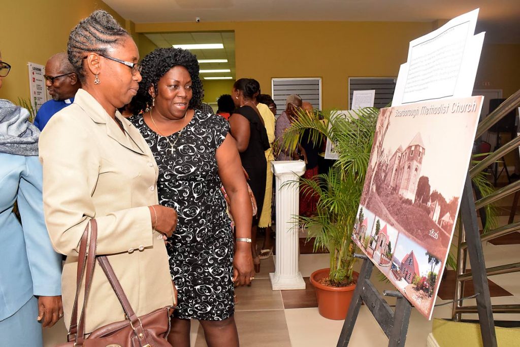 Reverend Janice Soyer- Delaney, left, and Reverend Esther Moore-Roberts, chairman of the Tobago Christian Council, Moravian Church view a photograph of the evolution of the Scarborough Methodist church at the opening of the exhibit 