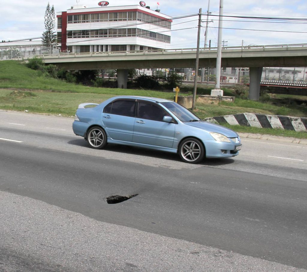 SINKHOLE ALERT: A car passes by a small sinkhole which has developed on the westbound lane of the Beetham Highway.