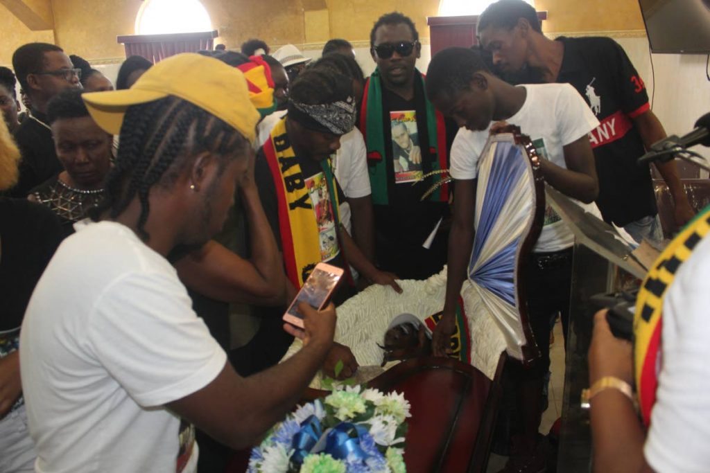 Friends and relatives of Akiel “Alkaline” Thomas view his body at his funeral held at Simpson’s Funeral Home in Laventille yesterday.