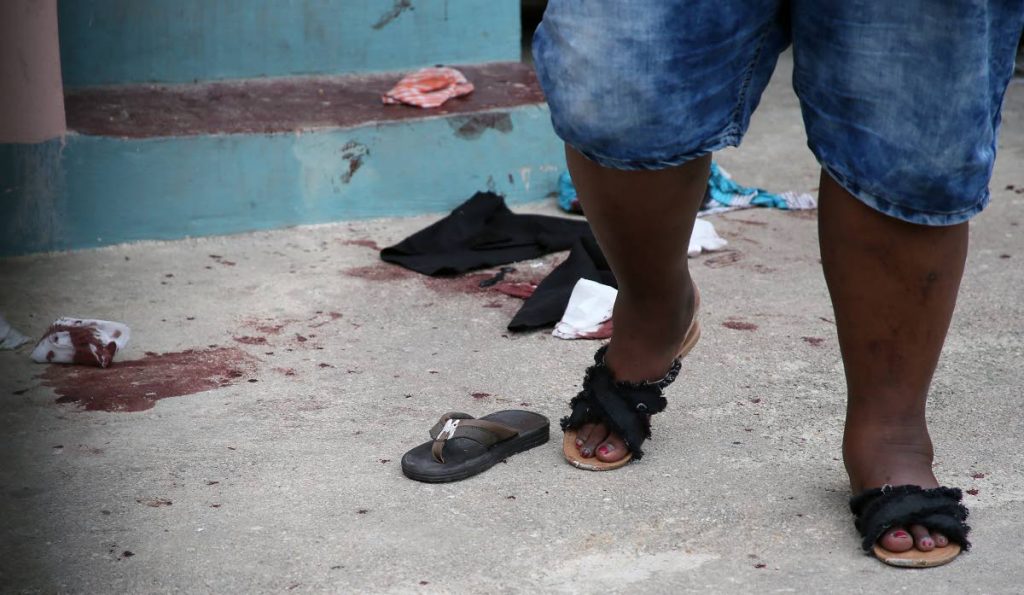 A woman walks past bloodstains and scattered shoes at a private home for the metally ill in Santa Cruz where seven people were stabbed yesterday. PHOTO BY AZLAN MOHAMMED