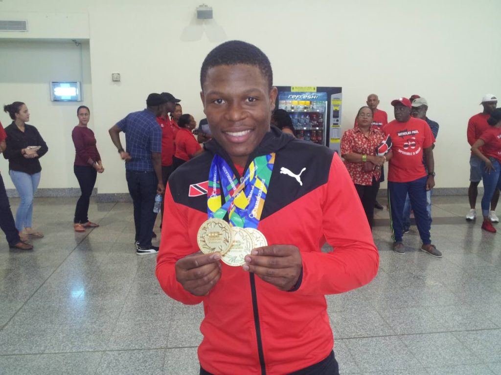 GOLD GALORE: TT cyclist Nicholas Paul shows off his three CAC Games gold medals on his return at the Piarco International Airport yesterday from Colombia. 