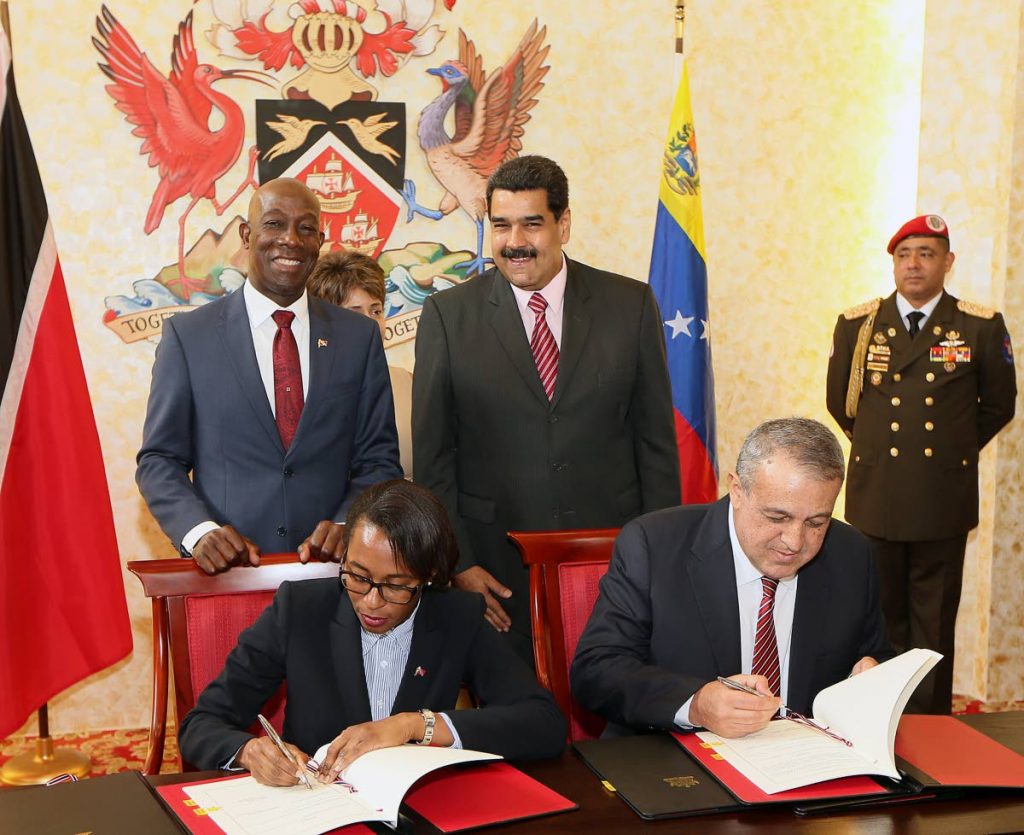 Venezuelan president Nicholas Maduro, right, and Prime Minister Keith Rowley in background looks on while Minister of Energy Nicole Olivere and   Venezula's Minister of Petroleum and Mining Eulogio del Pinosigns agreements document following  the  bi lateral meeting  TT government and Venezuela  at the Diplomatic center St Anns in May 2016.
PHOTO BY AZLAN MOHAMMED
