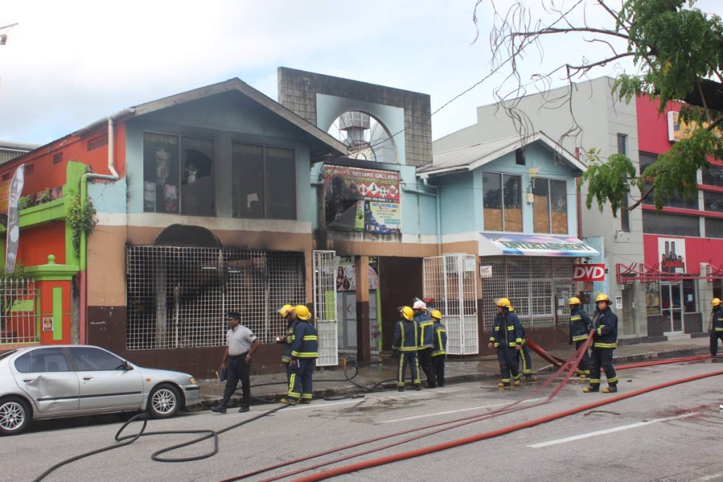Fire officers stand outside New City Mall in Port of Spain after putting out a fire, this weekend. Photo: Enrique Asson