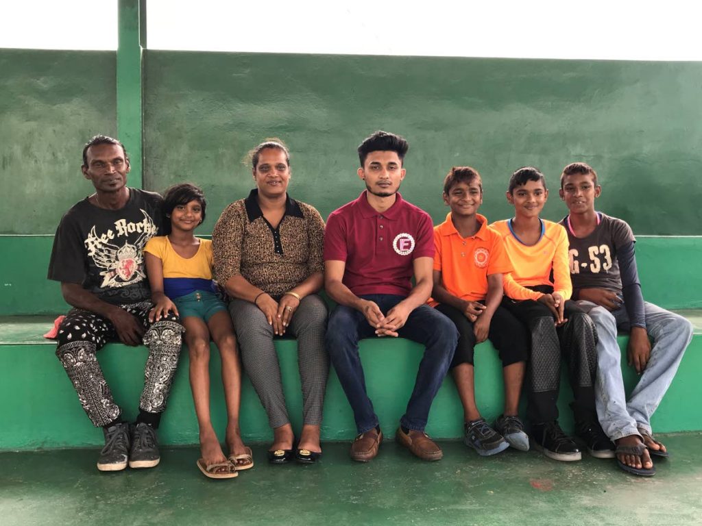 Nesar Hosein, centre, sits with the members of a family whose fruit stall was destroyed by fire. Hosein’s Life Foundation has provided assistance to the family.