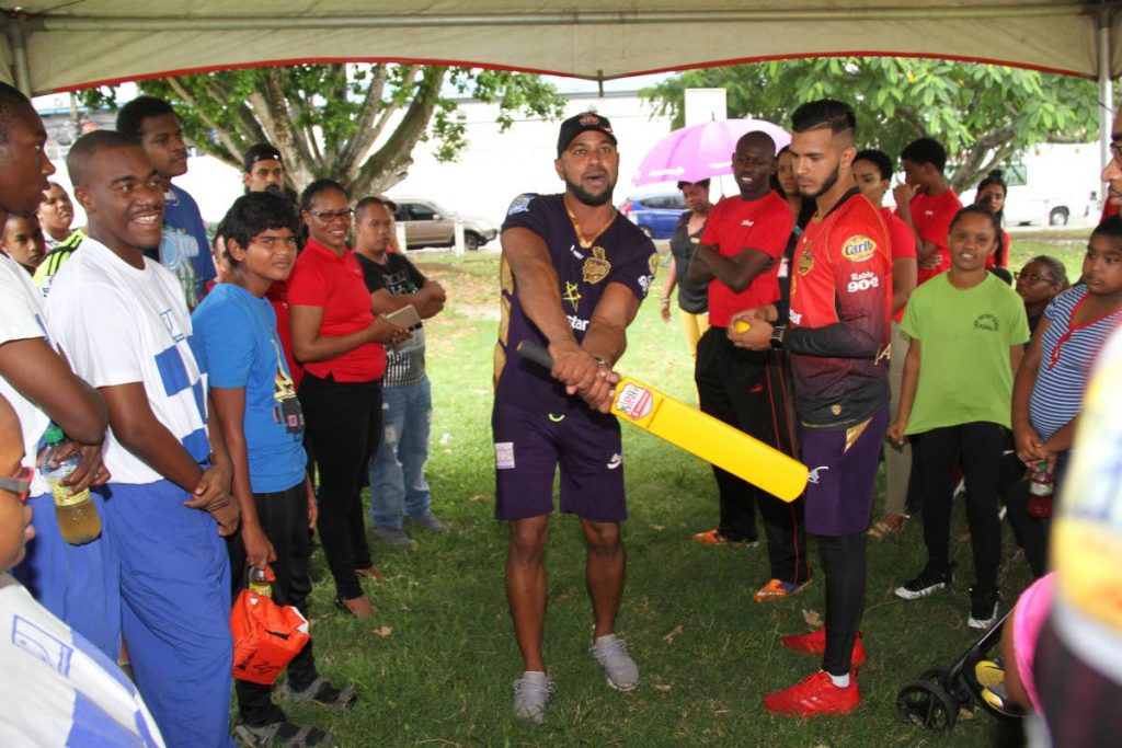 Coach of Trinbago Knight Riders, Imran Jan and player Amir Jangoo, right, demonstrate a batting technique at the Digicel Youth Cricket Series, at Nelson Mandela Park, St Clair, yesterday. Photo: SUREASH CHOLAI