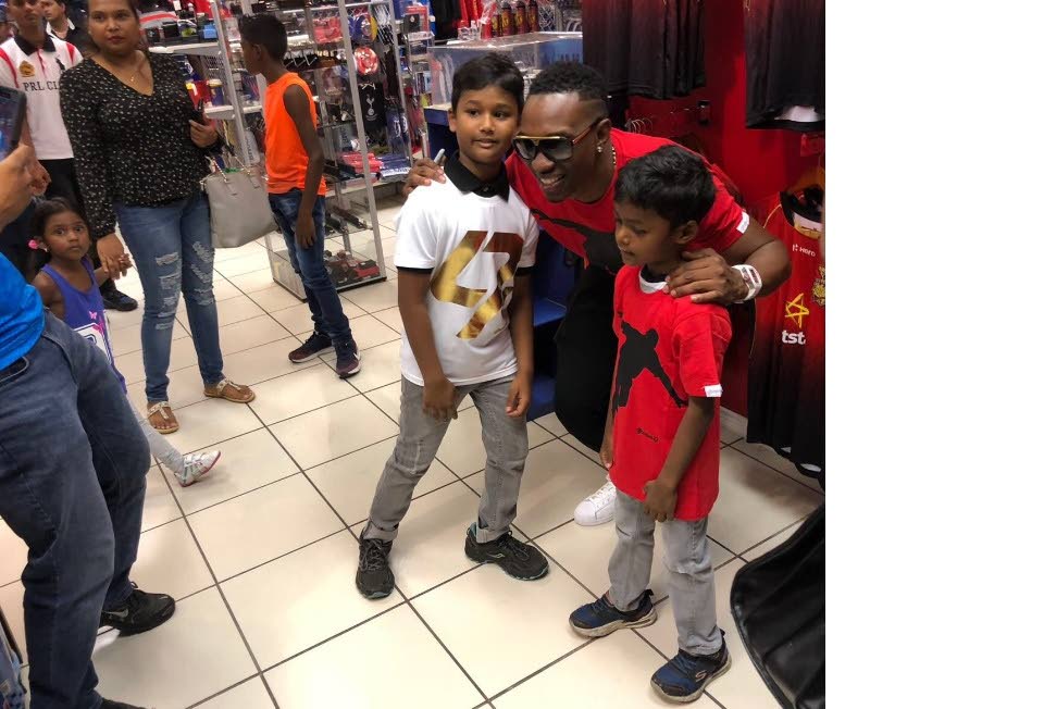 Trinbago Knight Riders captain Dwayne Bravo, centre, poses with fans wearing his official djbravo47 t-shirts at Fan Club, Chaguanas, yesterday.