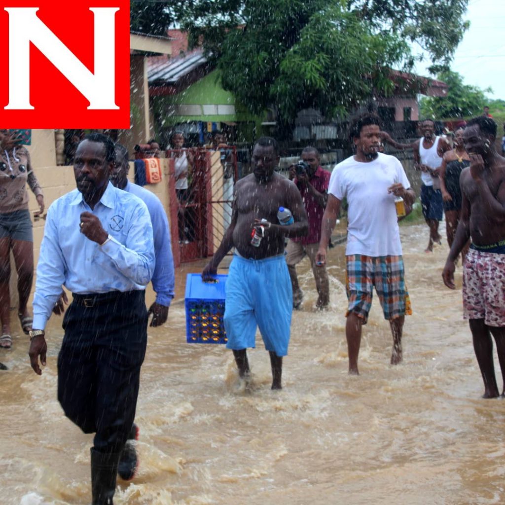 Acting Attorney General Fitzgerald Hinds walks hastily out of Beetham Gardens as group of men approach before dashing floodwater on him. PHOTO BY ENRIQUE ASSOON. 