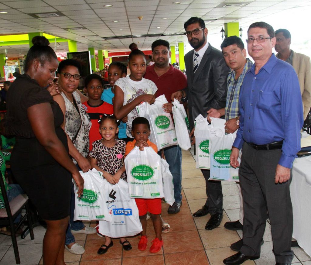 At right, president of the Greater San Fernando Area Chamber of Commerce Kiran Singh and other members pose for a photo with some children and their parents after they donated school supplies to them at RRM Plaza, High Street, San Fernando.