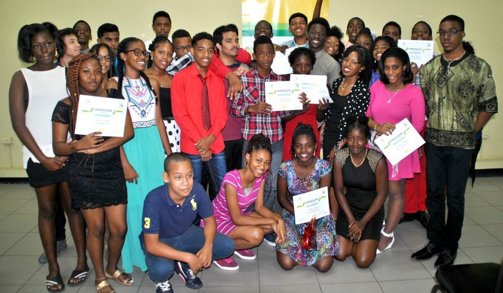 Happy graduates show off their Certificates of Achievement after graduating from the 2018 BPTT Young Adult Mathematics Experience at Diego Martin.  Sharing in the excitement is tutor Hilary Roberts (third from right – middle row).
