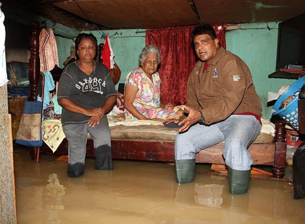 GULLY ASSISTANCE: Oropouche West MP Dr Roodal Moonilal comforts Gully Gokool and a relative, whose house at  SS Erin Road, Debe, was flooded on Tuesday trapping the elderly woman in her bedroom.