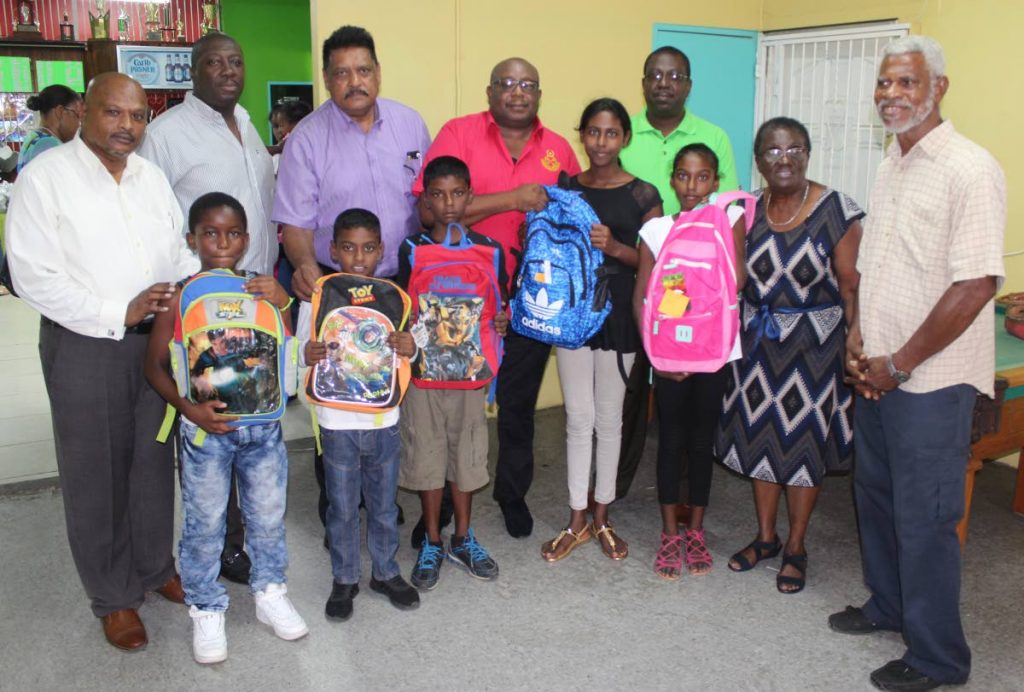 Krishna Bedassie, (at back left to right), Hayden Walcott, acting deputy Prisons Commissioner Mookish Pulliah, acting Prisons Commissioner Dane Clarke, Sherwin Bruce, Pastor Cynthia Cardogan and her husband with  several children who received backpacks with school supplies at Prisons Sports Complex, Arouca yesterday. PHOTO BY ENRIQUE ASSOON