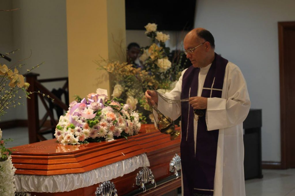 Fr Stephen Geofroy incenses Patricia Worrell’s coffin during her funeral at the J.E. Guide funeral home in San Fernando yesterday.