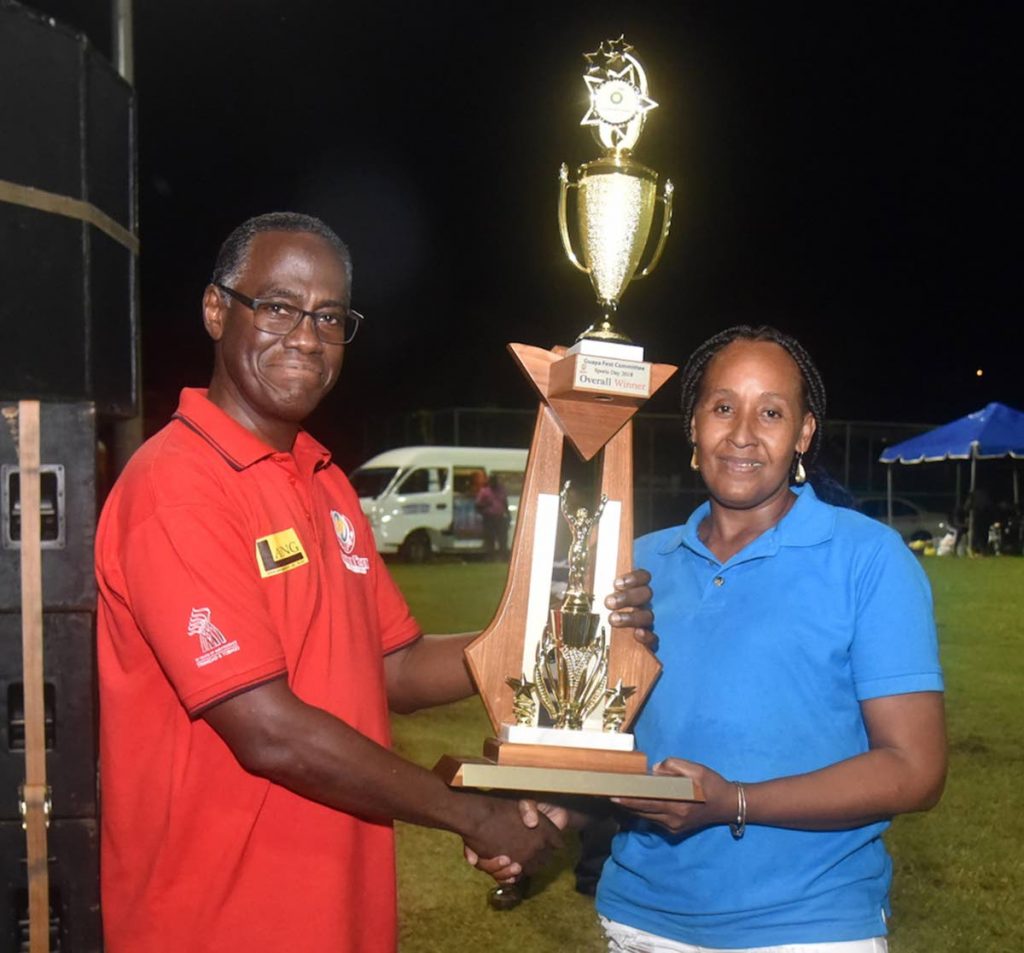 Happy Team manager Stacy Lett receives the championship trophy, on behalf of community team Piece Ah Cake, at GuayaFest Sports and Family Day from GuayaFest Committee president Raymond Cozier on Saturday.