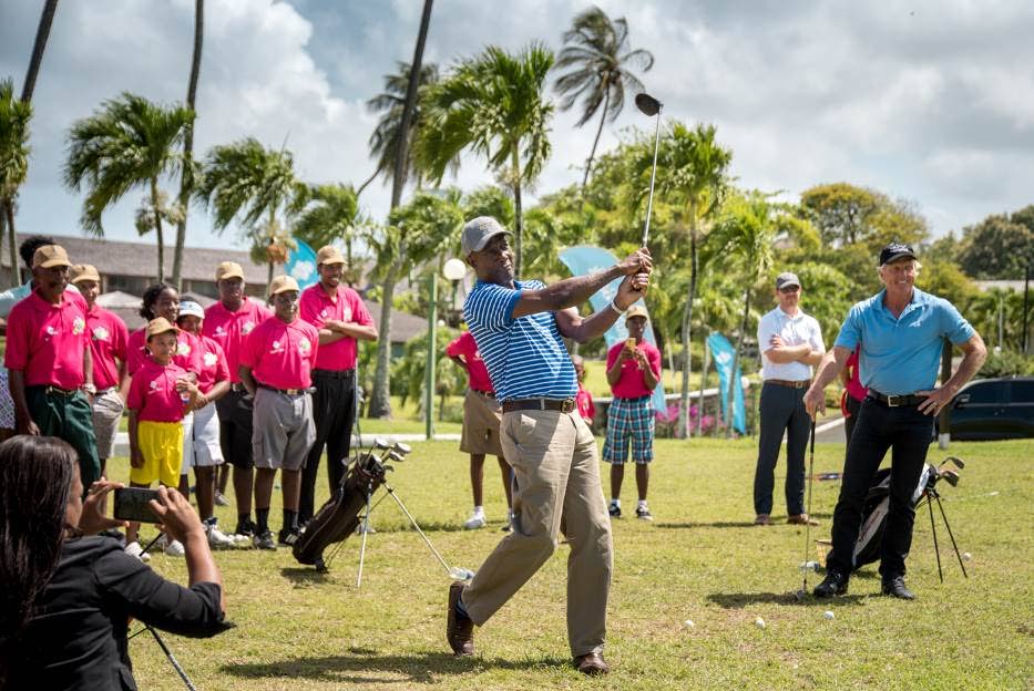 Prime Minister Dr Keith Rowley tests his skills as pro golfer Greg Norman,right, and participants of the Republic Bank Jane Young Tobago Junior Golf Programme look on, at the Mount Irvine Bay Resort Golf Course, Tobago, on Thursday.`
Photo courtesy Republic Bank