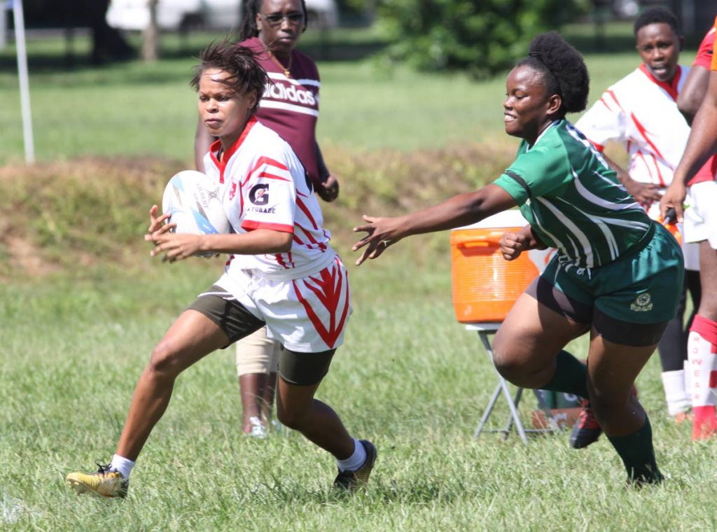 A Caribs player, left, eludes her Harvard rival in a TT Rugby Football Union women's championship division knockout semi-final on Saturday at the Queen's Park Savannah, Port of Spain. 