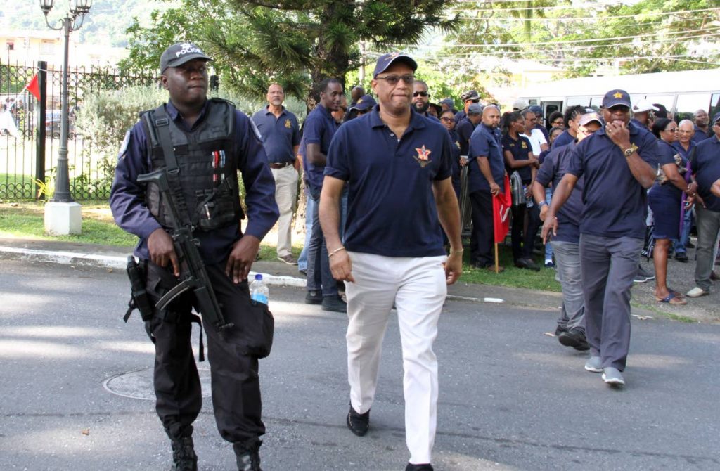 OWTU president general Ancel Roget walks with a policeman after arriving outside the official residence of the Prime Minister at La Fantasie Road, St Ann’s for an evening of prayers with the union’s membership on Sunday. PHOTO BY SUREASH CHOLAI
