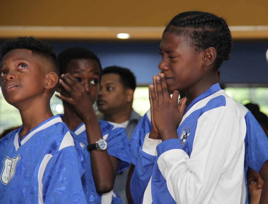 Students of the Arima Boys’ Government Primary School cry at the funeral for their football and cricket coach, Courtney Chadee, who died one week ago.