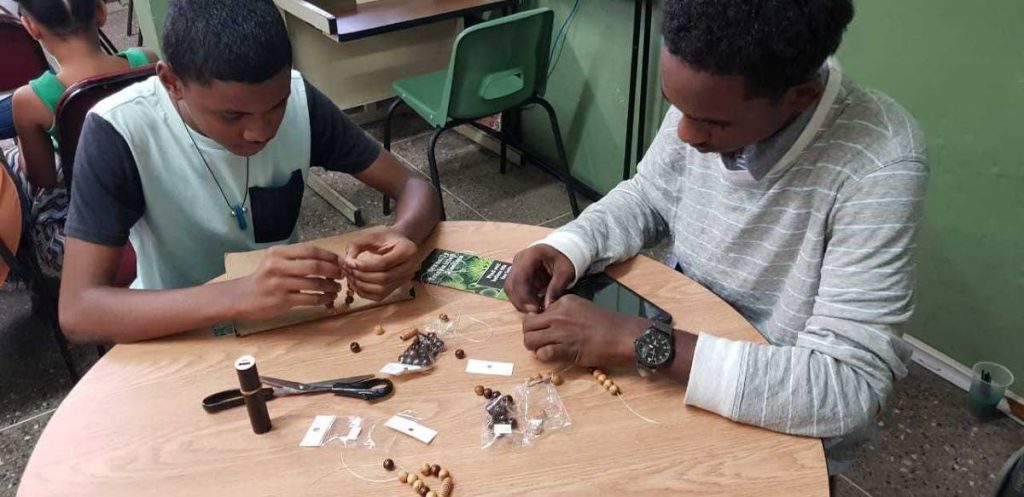 Young adult library camp participants attempt jewellery making at the Siparia Public Library.