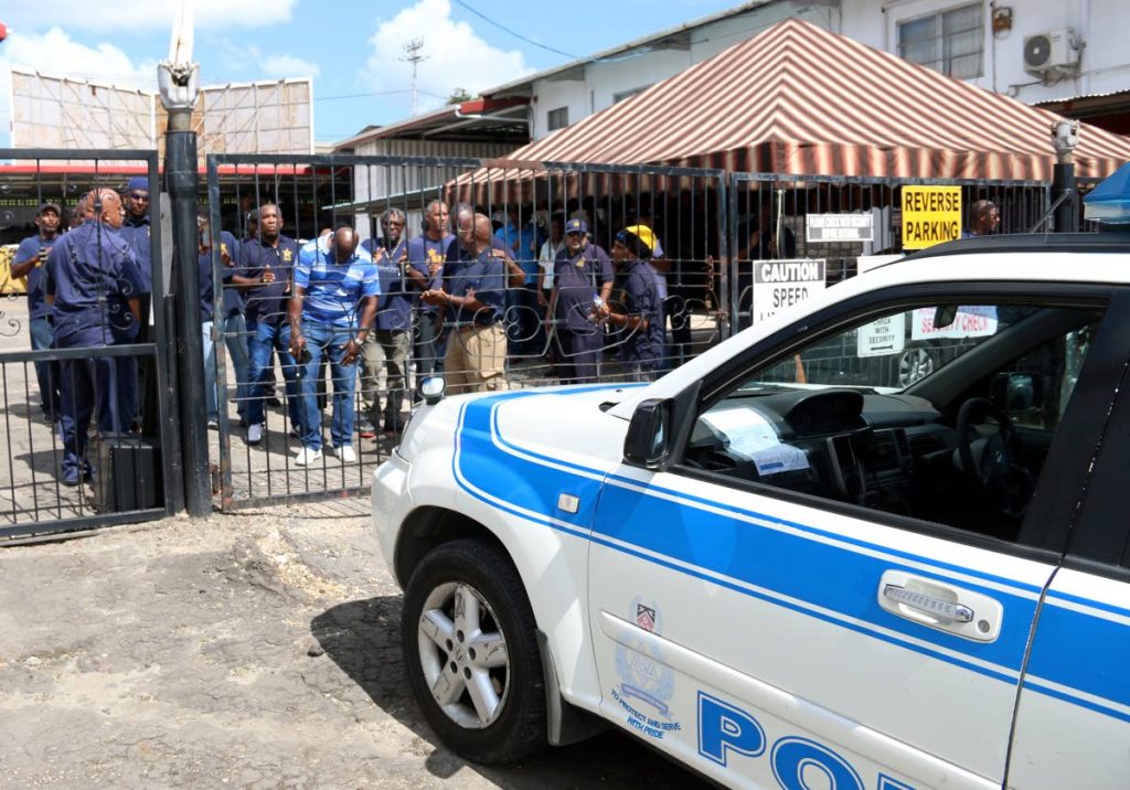 MONEY WOES: Lennox Petroleum Services workers and representatives of their union, the OWTU, protest under the watchful eyes of police at the company's Margaret Street, San Fernando office yesterday.   PHOTO BY ANSEL JEBODH