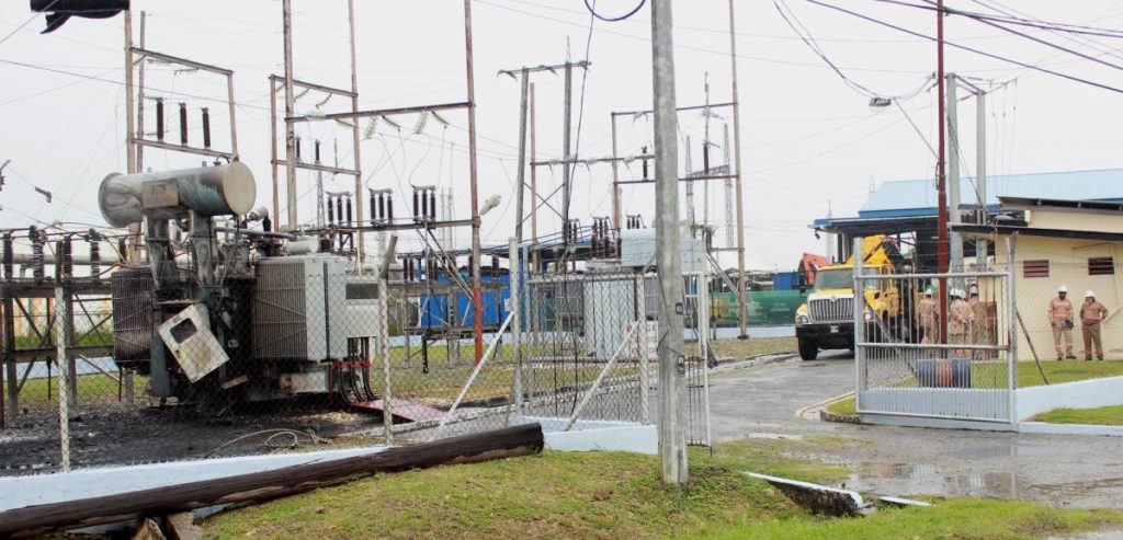 Fire out: TTEC workers, at right, shelter from the rain at an office near a substation which had been on fire earlier on Friday North Sea Drive, Point Lisas. PHOTO BY CHEQUANA WHEELER