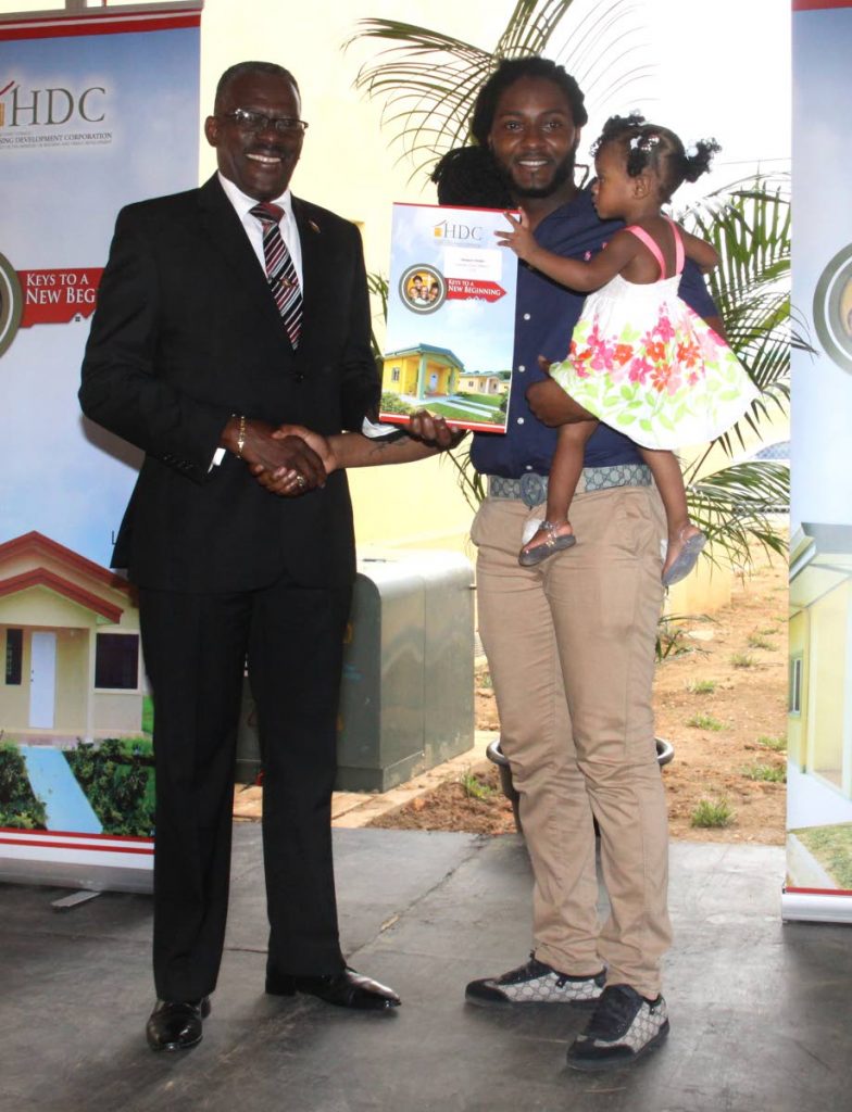 HOME WITH DADDY: Shomari Holder and his daughter receive their package for their new home at Nepuyo Court, Malabar last Wednesday, from Housing Minister Edmund Dillon.     PHOTO BY ANGELO MARCELLE